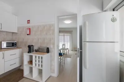 a kitchen with a white refrigerator and a table at Refúgio Estrela do Mar in Quarteira
