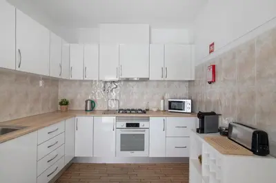 a white kitchen with white cabinets and appliances at Refúgio Estrela do Mar in Quarteira