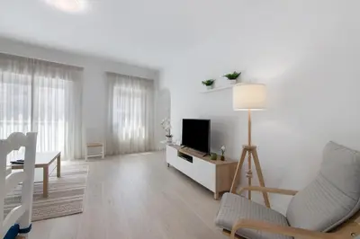 a white living room with a television and a table at Refúgio Estrela do Mar in Quarteira