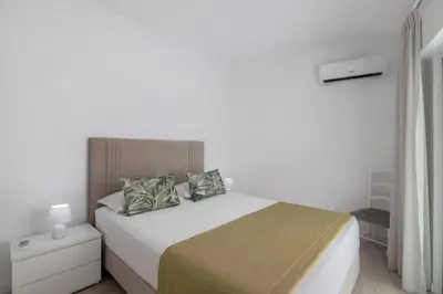 a white bedroom with a large bed with two pillows at Refúgio Estrela do Mar in Quarteira