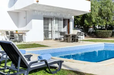 a pool with chairs and a table and a house at TAC - Villa Oura in Albufeira