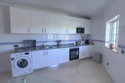 a kitchen with white cabinets and a washing machine at 3 Bed Vacation home in Quarteira in Quarteira