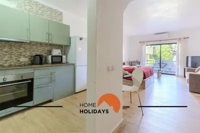 a kitchen with green cabinets and a living room at #287 Rodrimar Studio 212 by Home Holidays in Albufeira