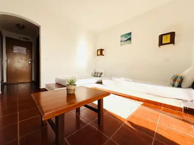 a room with two beds and a wooden table at Resort Albufeira Praia Oura in Albufeira