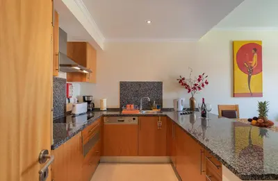 a large kitchen with wooden cabinets and granite counter tops at Vista das ondas 205 by AS in Olhos de Água