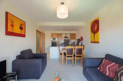 a living room with two blue couches and a kitchen at Vista das ondas 205 by AS in Olhos de Água