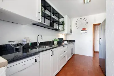 a kitchen with white cabinets and a clock on the wall at Alta Oura in Albufeira