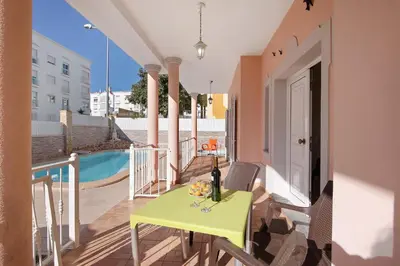 a yellow table and chairs on a balcony with a pool at Solar das Andorinhas in Albufeira
