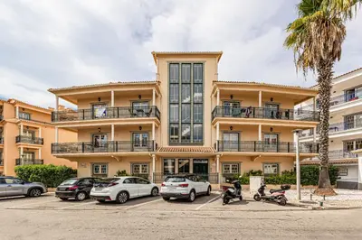 a large building with cars parked in a parking lot at Oasis Apartment in Albufeira
