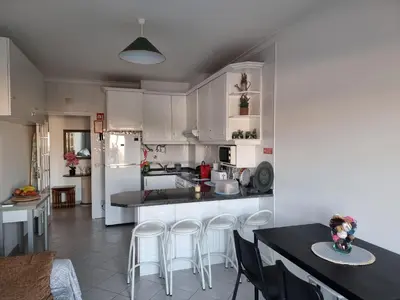 a kitchen with white cabinets and a table and chairs at Mar à Vista Apartment in Albufeira