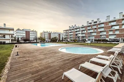 an outdoor deck with chairs and a swimming pool at Albufeira Green Dream Pool, Balcony & BBQ in Albufeira