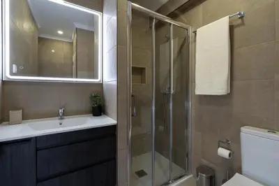 a bathroom with a sink and a glass shower at Mello Apartamento renovado, praia de Quarteira in Quarteira