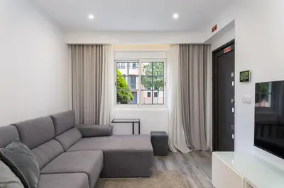 a living room with a gray couch and a window at Casa dos Avós - Faro Relax & Comfort in Faro