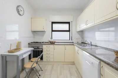 a kitchen with white cabinets and a chair in it at Areias de São João 2BR Apartment - Shared Pool & Terrace, by Hopstays in Albufeira