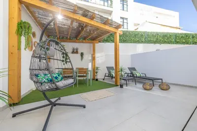 a patio with a swing and a table and chairs at Roots Apartments in Faro