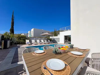 a wooden table with plates on it next to a pool at Luxury 4-Suite Villa, Pool, Jacuzzi, Games Room in Albufeira