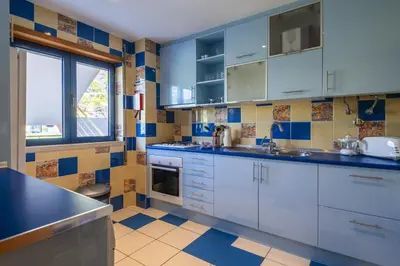 a kitchen with white cabinets and blue and yellow tiles at Marina Orada Apartment with Pool - 900m from the Beach in Albufeira