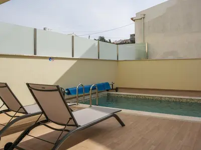 a pool with two chairs next to a swimming pool at Eco Residence 05 House by Stay ici Algarve Holiday Rental in Albufeira