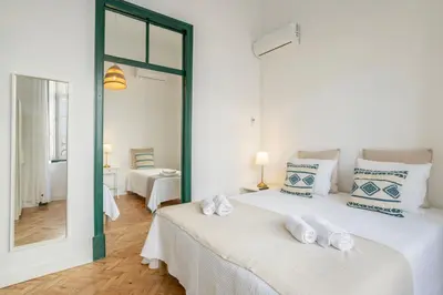 a white bedroom with two beds with white and blue pillows at Casa Dona Vitória in Faro