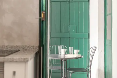 a table with two cups on it next to a green door at Casa Dona Vitória in Faro
