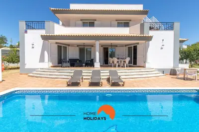 a villa with a swimming pool in front of a house at #297 Espaçosa Vivenda V5 by Home Holidays in Albufeira
