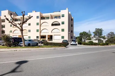 a large white building with cars parked in front of it at Sunrise Salgados Village in Galé