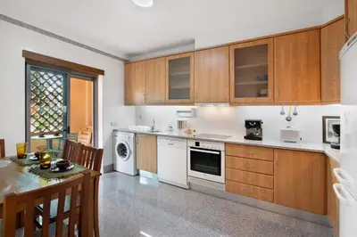 a kitchen with wooden cabinets and a table with chairs at Apart Condomínio do Vale in Guia