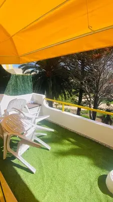 two chairs sitting on a balcony with green grass at Apartamento relaxante com terraço e próximo da praia, no 2º andar in Quarteira