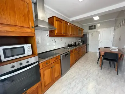a kitchen with wooden cabinets and a table with a microwave at Casa da Baixa in Faro