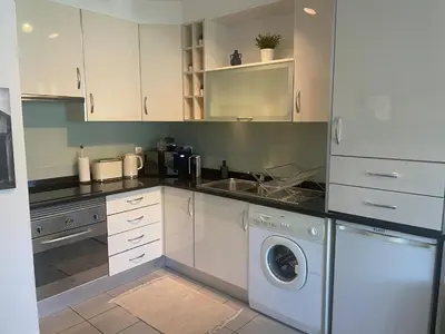 a kitchen with white cabinets and a washing machine at Casa Ligia in Vilamoura