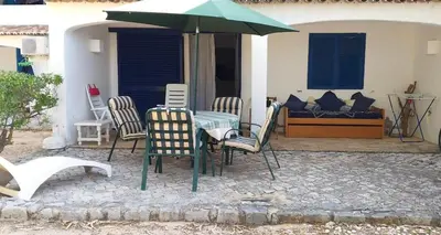 a table with chairs and an umbrella on a patio at Balaia Gardens in Albufeira in Albufeira