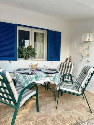 a table and chairs in a room with blue shutters at Balaia Gardens in Albufeira in Albufeira