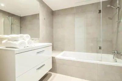 a white bathroom with a tub and a sink at The Green Escape Albufeira Poolside Retreat in Albufeira