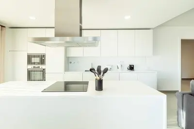 a white kitchen with a counter with utensils on it at The Green Escape Albufeira Poolside Retreat in Albufeira