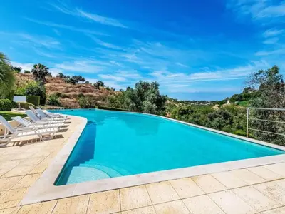 a swimming pool with lounge chairs next to a mountain at Villa Maria, 3BD & Pool & Garden & BBQ in Albufeira