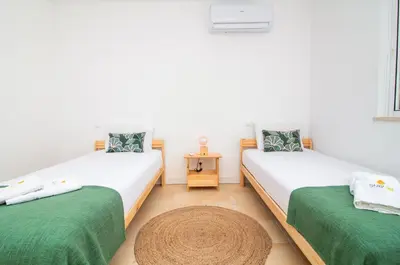 two beds in a room with green sheets at Villa Maria, 3BD & Pool & Garden & BBQ in Albufeira