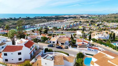 a kitchen with white cabinets and a clock on the wall at Stunning Sunrise & Sunset Rooftop Condo by BeCherish in Albufeira