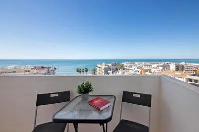 a table and chairs on a balcony with a view of the ocean at 1 Bedroom Seaview Apartment in Quarteira