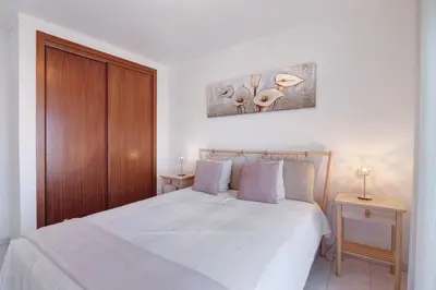a bedroom with a white bed with two night stands at 1 Bedroom Seaview Apartment in Quarteira
