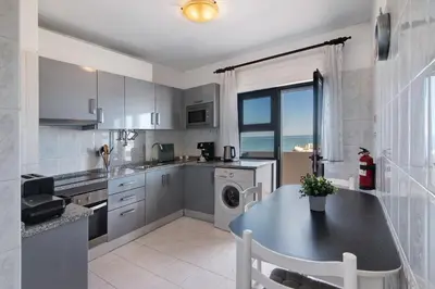 a kitchen with a table and a sink and a dishwasher at 1 Bedroom Seaview Apartment in Quarteira