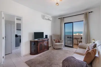 a living room with a couch and a television at 1 Bedroom Seaview Apartment in Quarteira