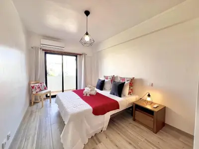 a bedroom with a bed with a red blanket at Quarteira Brightness by Homing in Quarteira