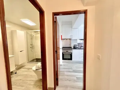 a bathroom with a toilet and a kitchen at Quarteira Brightness by Homing in Quarteira