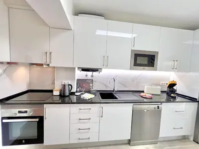 a white kitchen with white cabinets and a sink at Quarteira Brightness by Homing in Quarteira