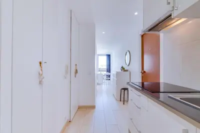 a kitchen with white cabinets and a black counter top at T1 Edificio Loulé - centro de Vilamoura in Vilamoura