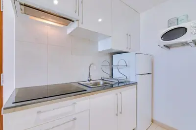 a white kitchen with a sink and a refrigerator at T1 Edificio Loulé - centro de Vilamoura in Vilamoura