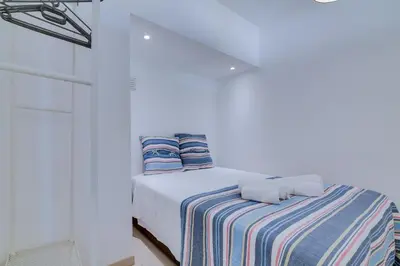 a white bedroom with a bed with a striped blanket at T1 Edificio Loulé - centro de Vilamoura in Vilamoura