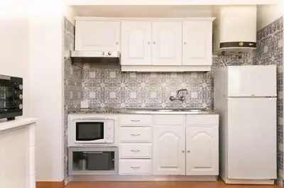 a white kitchen with white cabinets and a refrigerator at BeGuest Sea Breeze Apartment in Albufeira