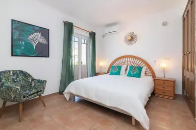 a bedroom with a bed and a chair and a window at Villa Terramar - Golden & Salty in Guia