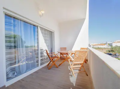 a balcony with a table and chairs and a large window at Boho house, Albufeira in Albufeira